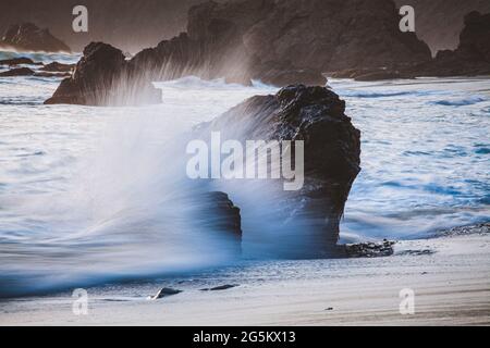 Am Strand Big Sur, Kalifornien, platschen Wellen gegen Felsen Stockfoto