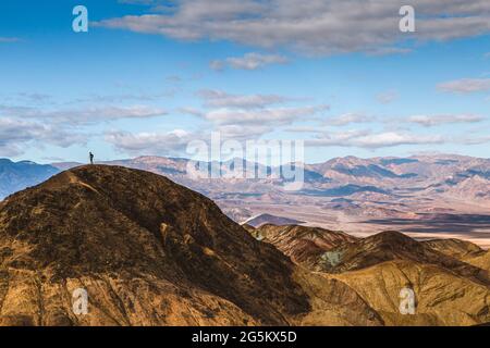 In der Weite des Death Valley steht eine kleine, kleine Einzelperson auf dem Gipfel. Stockfoto