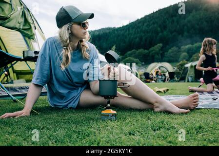 Frau saß mit einem tragbaren Herd während des Campens in Snowdonia Stockfoto