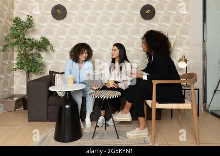 Glückliche Geschäftsfrauen sitzen auf einer Couch im Büro und arbeiten zusammen. Bürokonzept. Stockfoto