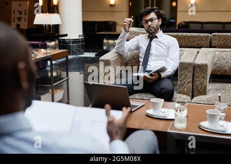 Porträt von zwei Geschäftsleuten, die am Tisch in der Hotellounge arbeiten Stockfoto