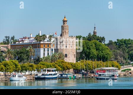 Blick über den Fluss Rio Guadalquivir auf der Promenade mit Ausflugsbooten und Torre del Oro, Sevilla, Andalusien, Spanien, Europa Stockfoto