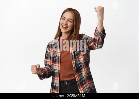 Junge glückliche Frau pumpt mit der Faust, lacht und lächelt, jubelt oder brüllt für das Team, schaut beiseite in den Kopierraum, feiert, triumphiert, steht Stockfoto