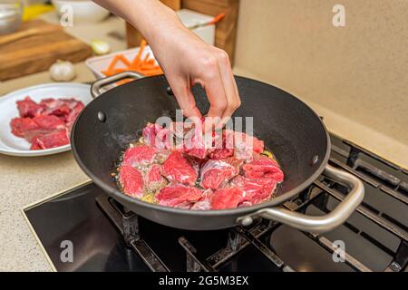 Kochen Pilaf in einem Kessel. Ein Schritt für Schritt Rezept für das Kochen Pilaf, schneiden Sie das Rindfleisch in Stücke und braten in einem Kessel, Fleisch für Pilaf.Kochen Pilaf an Stockfoto