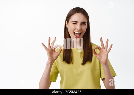 Sie garantiert keine Probleme. Junge Frau zwinkernd und zeigen OK OK Zeichen, versichern alles unter Kontrolle, alles gut, empfehlen smth, Lob große Arbeit Stockfoto