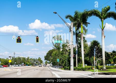 Palmen auf der Straße in Bonita Springs, Florida mit Schild für die berühmte Barefoot Beach Stadt am Tag in Collier County mit blauem Himmel im Frühling Stockfoto