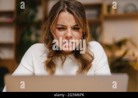 Frustriert verwirrt junge Managerin Blick auf Laptop-Computer, während Am Schreibtisch sitzen Stockfoto