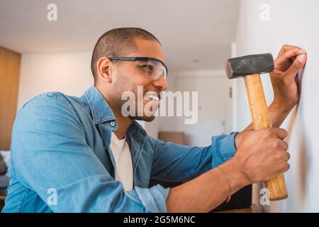 Lateinischer Mann, der Nagel an die Wand hagelt. Stockfoto