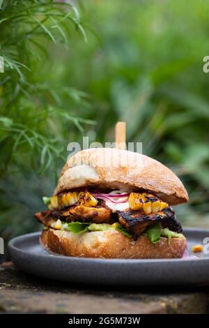 Rustikales Brötchen mit Chipotle-Huhn, gegrilltem Swet-Mais und Avocado Stockfoto