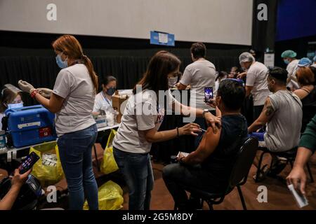 Gesundheitshelfer impfen Patienten mit dem Sinovac COVID-19-Impfstoff in einem Kino, das zu einer temporären Impfstelle in Manila, Philippinen, wurde. Stockfoto