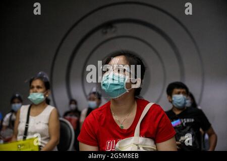 Patienten mit Schutzmasken als Vorsichtsmaßnahme gegen die Ausbreitung des Coronavirus beobachten eine physische Distanzierung, während sie sich anstellen, um eine Dosis des Sinovac COVID-19-Impfstoffes in einem Kino zu erhalten, das zu einer temporären Impfstelle in Manila, Philippinen, wurde. Stockfoto