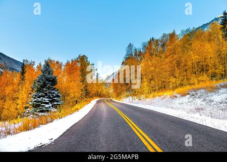 Blick auf die kastanienbraunen Glocken des Sonnenaufgangs in Aspen, Colorado, felsige Berge und Herbstansicht von orangegelben Blättern und winterschneegefrorene Bäume auf einer Fahrt durch den Bach Stockfoto