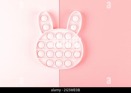 Neues Silcone Spielzeug Pop it in Form von Hase auf dem rosa Hintergrund. Neues sensorisches Anti-Stress-Spielzeug für Kinder und Erwachsene. Speicherplatz kopieren. Flach liegend. Stockfoto