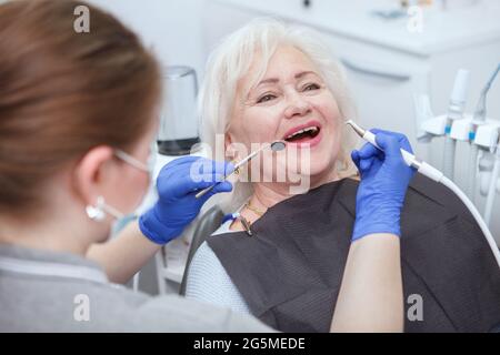 Glückliche ältere Frau bekommt Zahnbehandlung durch einen professionellen Zahnarzt Stockfoto