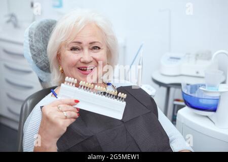 Schöne ältere Frau lächelt zur Kamera und bekommt Zahnaufhellung in der Zahnklinik Stockfoto