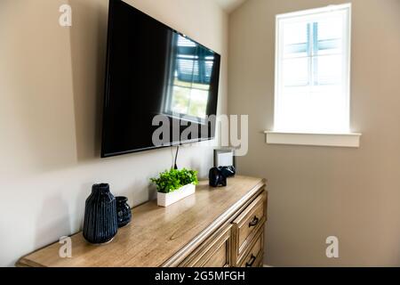 Tisch im kleinen Wohnzimmer oder Schlafzimmer mit stilvoller Gestaltung und niemand im Haus mit Fernseher an der Wand und neutralen Farben Stockfoto