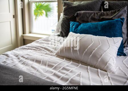 Nahaufnahme der neuen Bettdecke mit dekorativen weißen blauen Kissen im Schlafzimmer im modernen Stil von Haus, Haus oder Wohnung Stockfoto