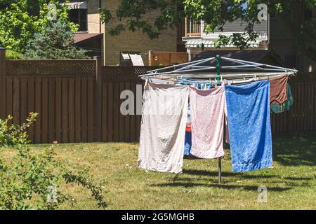 Metall-Wäscheständer für Outdoor-Kleidung mit Handtüchern und einem Hemd, das darauf trocknet. Auf dem Rasen im Hinterhof. Vintage-Filter. Stockfoto