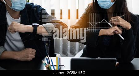 Unternehmen oder Buchhalter tragen eine Maske und stoßen Ellbogen, um soziale Distanz zu halten, anstatt Umarmungen oder Handschlag am Morgen im Heimbüro. Stockfoto