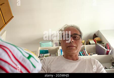 mature man in room placing clothes in a drawer seen from inside Stockfoto