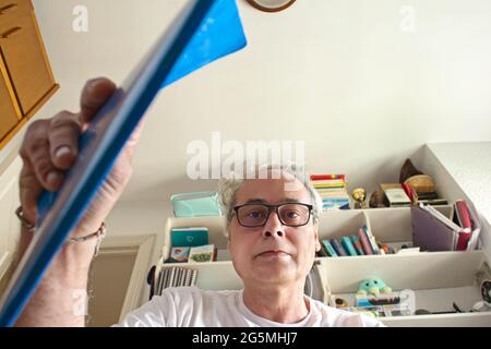 mature man in room placing a notebook in a drawer seen from inside Stockfoto