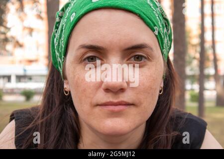 Nahaufnahme im Hochformat. Schöne junge Frau ohne Make-up in einem schwarzen T-Shirt und einem grünen Kopfschmuck von der Sonne an einem sonnigen Sommertag im Freien. Sonnenlicht Stockfoto