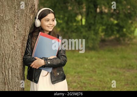 Mädchen hören Audio tragen Lehrbücher entspannend Park Hintergrund, Schulleben Konzept Stockfoto