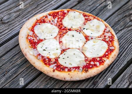 Frische Kruste ganze kleine Pizza auf dem Tisch mit geschmolzenem Mozzarella-Käse und Streuseln und rote Tomatensauce in der Nähe als italienische Küche Stockfoto