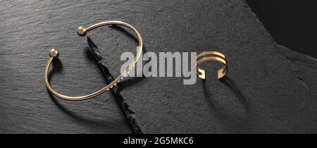 Goldenes Armband mit Diamanten und doppeltem Ring auf schwarzen Steintabletts Stockfoto