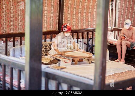 Kemer, Türkei - 25. Mai 2021: Frau bereitet im Freien nationales türkisches Fladenbrot zu. Teigvorbereitung. Türkische kulinarische Traditionen in der Küche. High qu Stockfoto