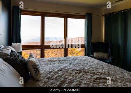 Rustikales Appartementhaus mit Schlafzimmer-Fensterblick vom Bett von Wintergreen, Virginia blauer Bergrücken im Herbst mit orangefarbenem Laub Stockfoto