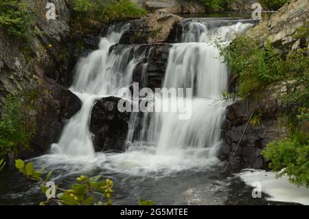 Wasserfall bricht durch die Felsen am Ende eines kleinen Baches im Wald. Stockfoto