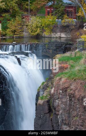 Wasserfall und Klippen mit einem roten Haus im Hintergrund in Patterson, New Jersey Stockfoto