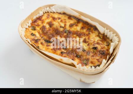 goldene Farbe auf gebackene Lasagne, bereit, in Holzbehälter auf weißem Hintergrund zu dienen Stockfoto