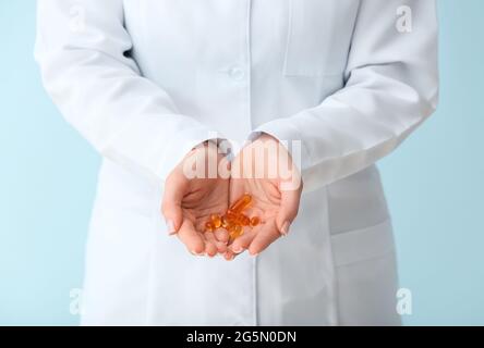 Ärztin hält Fischölpillen auf farbigem Hintergrund, Nahaufnahme Stockfoto