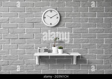 Regal mit Schlüsseln und Zimmerpflanzen, die an einer Ziegelwand hängen Stockfoto