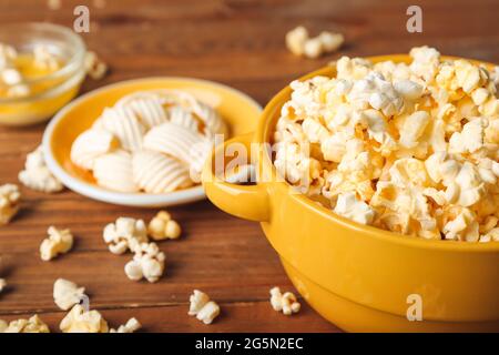 Schüsseln mit leckerem Popcorn und Butter auf Holzhintergrund Stockfoto