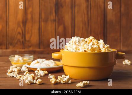 Schüsseln mit leckerem Popcorn und Butter auf Holzhintergrund Stockfoto