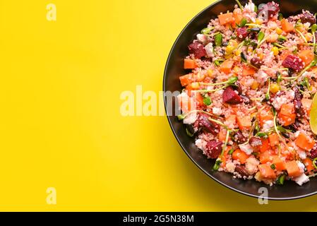 Schüssel mit Couscous und Gemüse auf farbigem Hintergrund Stockfoto