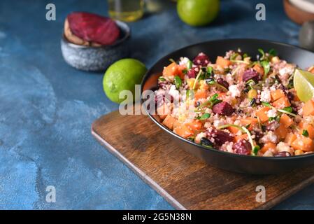 Schüssel mit Couscous und Gemüse auf farbigem Hintergrund Stockfoto