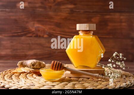Schüssel und Glas Honig mit Dipper auf Holzboden Stockfoto