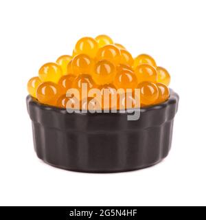 Gelbe Tapiokaperlen für Bubble Tea isoliert auf weißem Hintergrund. Tapioka-Perlen in schwarzer Keramikschale. Stockfoto