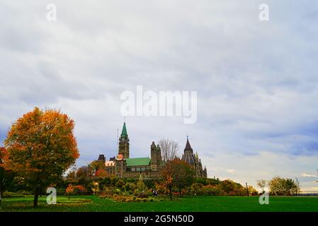 Ein Fernblick auf den Parliament Hill. Grünes Gras, rote Blätter, weiße Wolken.Herbstansicht der Stadt Ottawa, Kanada. 2016. Stockfoto