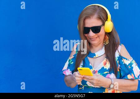 Ältere hispanische Frau hört Musik am Telefon auf der Straße. Stockfoto