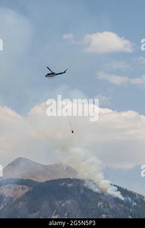 Ein Bell 205-A1 Feuerwehrhubschrauber fliegt hinein, um bei einem Waldbrand in den La Sal Mountains in Utah Wasser abzulassen. Stockfoto