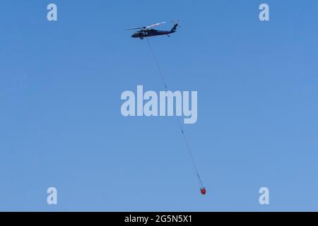 Ein Sikorsky UH-60 Blackhawk Feuerlöschhubschrauber trägt einen Helibucket, um Wasser auf ein Waldfeuer in Utah zu werfen. Stockfoto