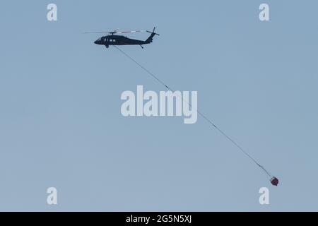 Ein Sikorsky UH-60 Blackhawk Feuerlöschhubschrauber trägt einen Helibucket, um Wasser auf ein Waldfeuer in Utah zu werfen. Stockfoto