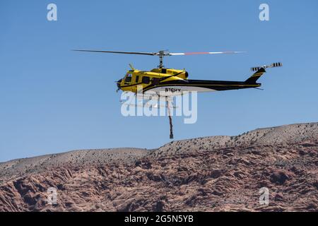 Ein Hubschrauber vom Typ Bell 205-A1, der für die Feuerunterdrückung aus der Luft konfiguriert ist, mit einem flexiblen Schlauch zum Befüllen und Fallenlassen von Wasser im Feuer. Stockfoto