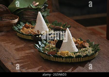 Reis in Kegelform. In Indonesien wurde „Nasi Tumpeng“ GENANNT, EIN festliches indonesisches Reisgericht mit Beilagen Stockfoto