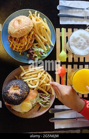 Verschiedene Burger mit Sandwich und Saft auf dem Holztisch, Blick von oben. Lebensmittelkonzept im Innenbereich Stockfoto